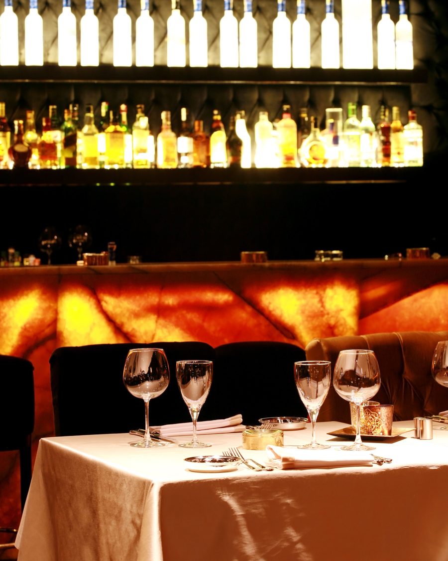 A set table in a restaurant lit by a wall of bottles
