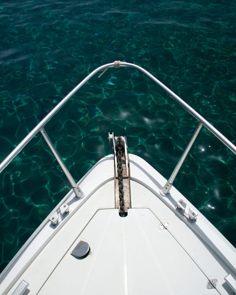 The bow of a yacht over clear green water